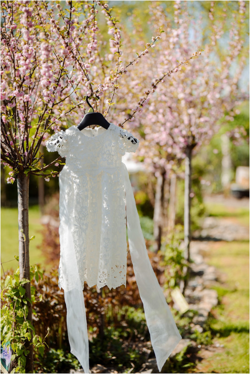 chrzest portret chrzest mała dziewczynka z wiankiem na głowie siedzi pod magnolią