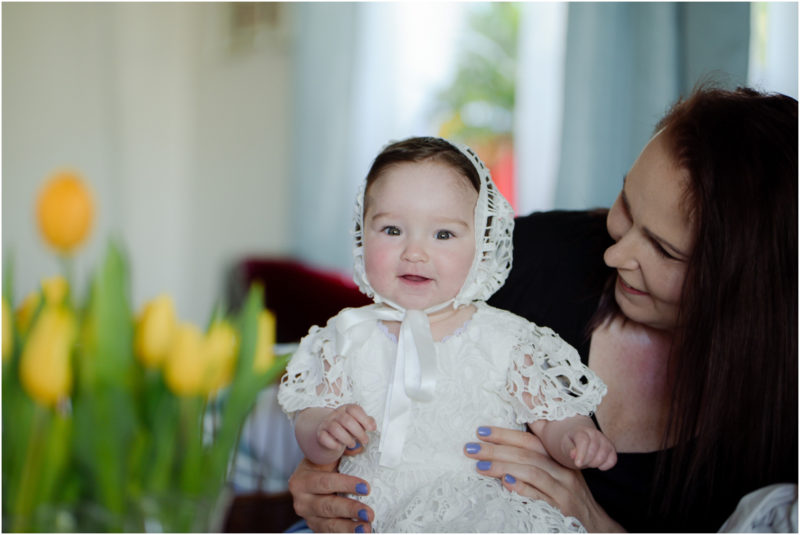 chrzest portret chrzest mała dziewczynka z wiankiem na głowie siedzi pod magnolią