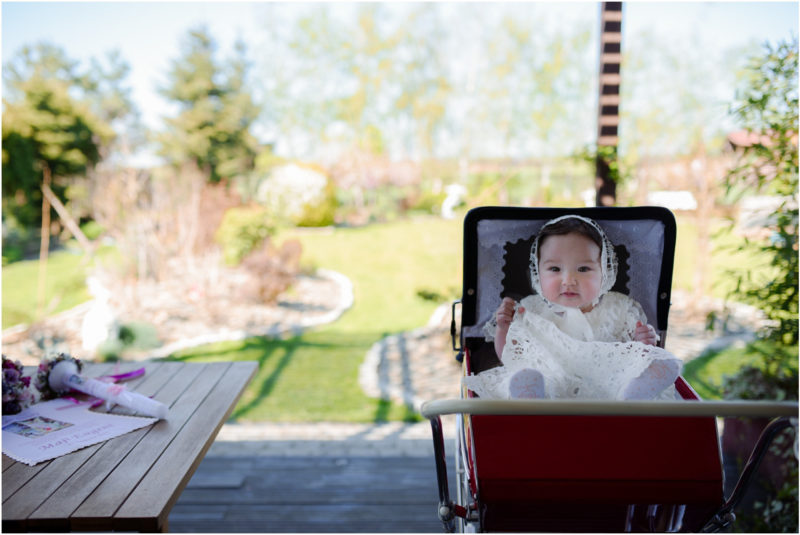 chrzest portret chrzest mała dziewczynka z wiankiem na głowie siedzi pod magnolią