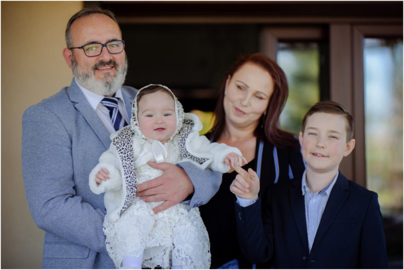 chrzest portret chrzest mała dziewczynka z wiankiem na głowie siedzi pod magnolią