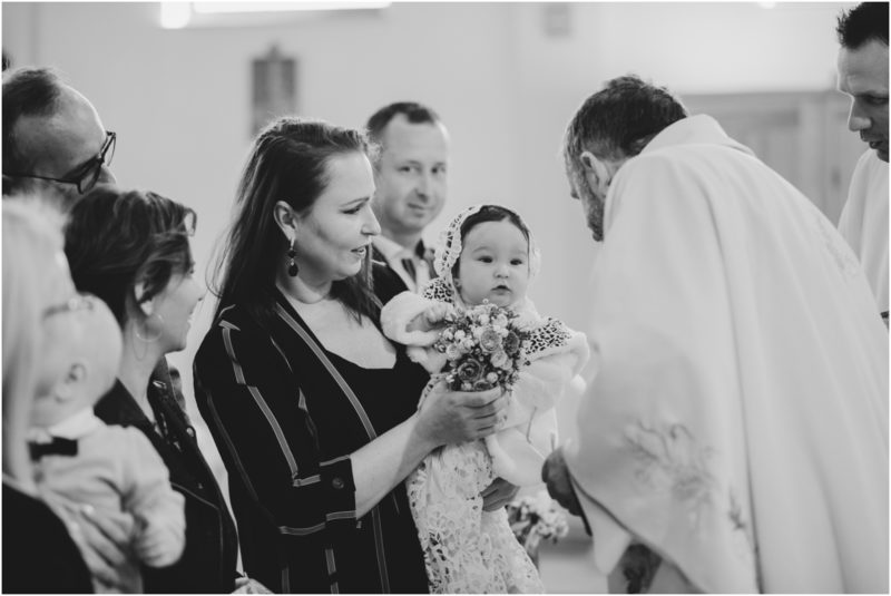 chrzest portret chrzest mała dziewczynka z wiankiem na głowie siedzi pod magnolią