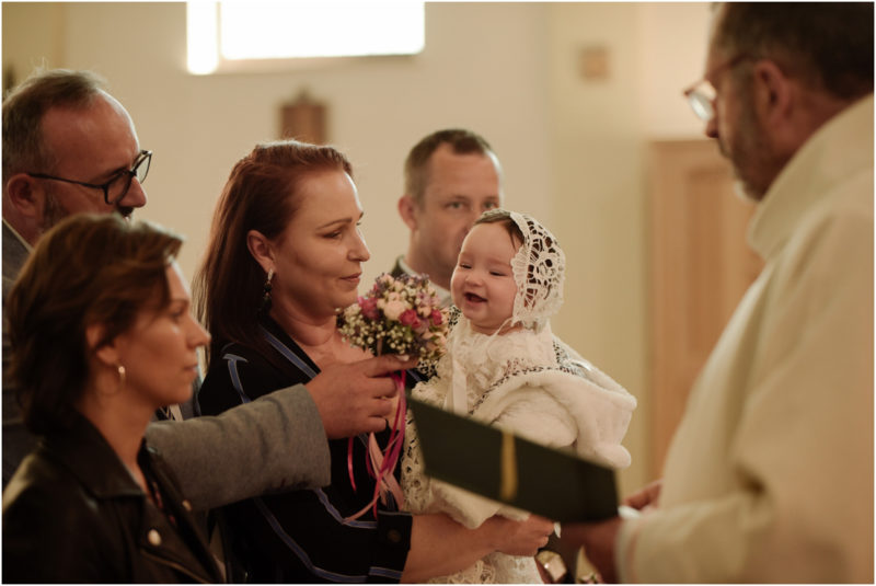 chrzest portret chrzest mała dziewczynka z wiankiem na głowie siedzi pod magnolią