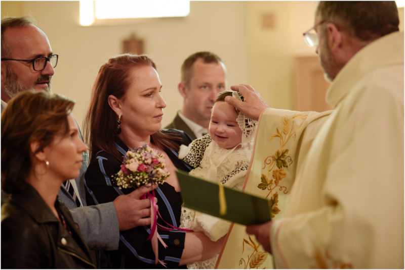 chrzest portret chrzest mała dziewczynka z wiankiem na głowie siedzi pod magnolią
