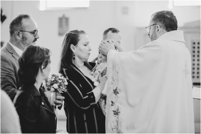 chrzest portret chrzest mała dziewczynka z wiankiem na głowie siedzi pod magnolią