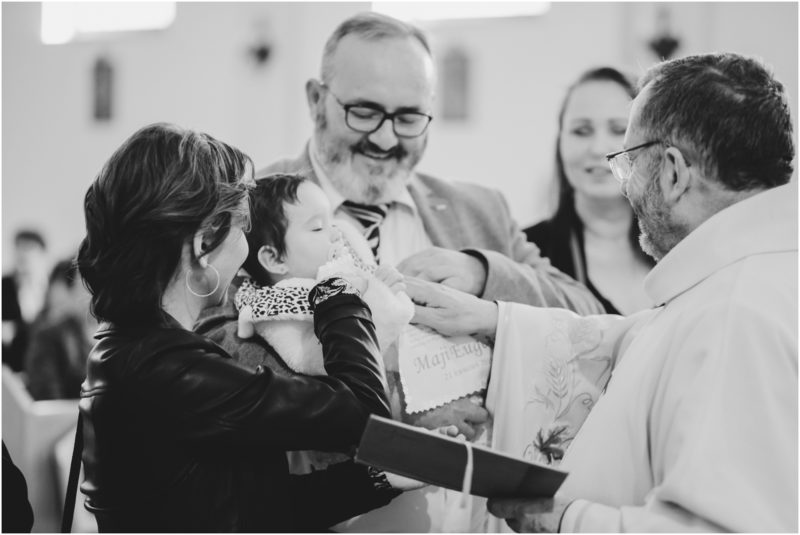 chrzest portret chrzest mała dziewczynka z wiankiem na głowie siedzi pod magnolią