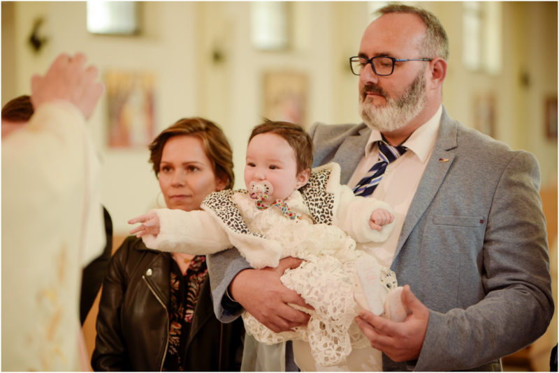 chrzest portret chrzest mała dziewczynka z wiankiem na głowie siedzi pod magnolią