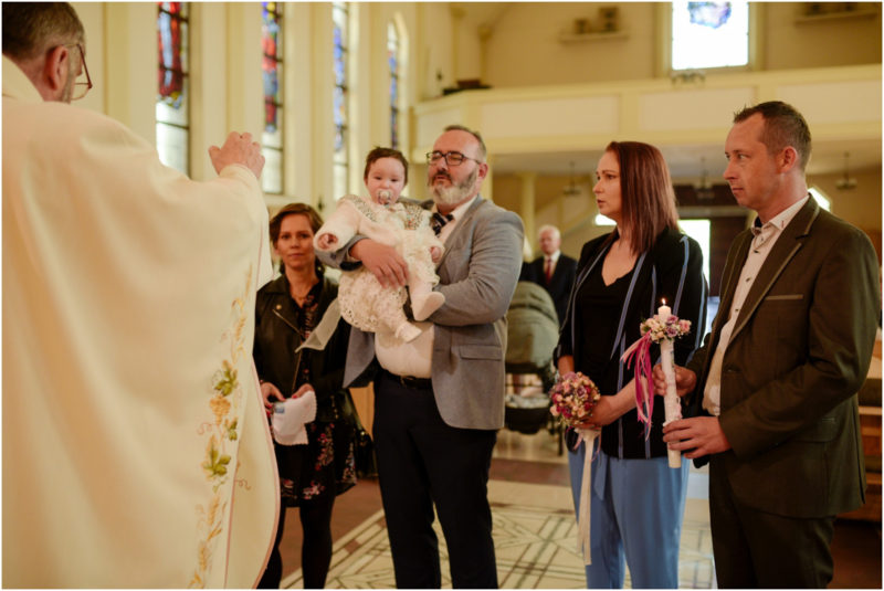 chrzest portret chrzest mała dziewczynka z wiankiem na głowie siedzi pod magnolią