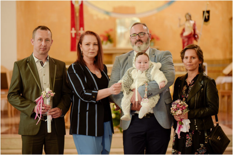 chrzest portret chrzest mała dziewczynka z wiankiem na głowie siedzi pod magnolią