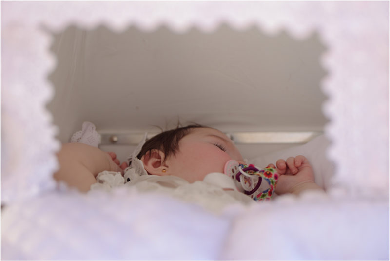 chrzest portret chrzest mała dziewczynka z wiankiem na głowie siedzi pod magnolią