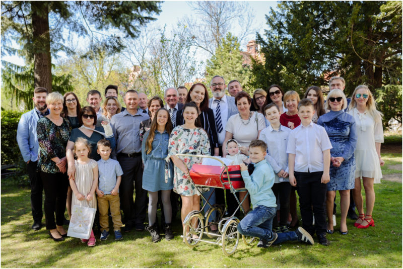 chrzest portret chrzest mała dziewczynka z wiankiem na głowie siedzi pod magnolią