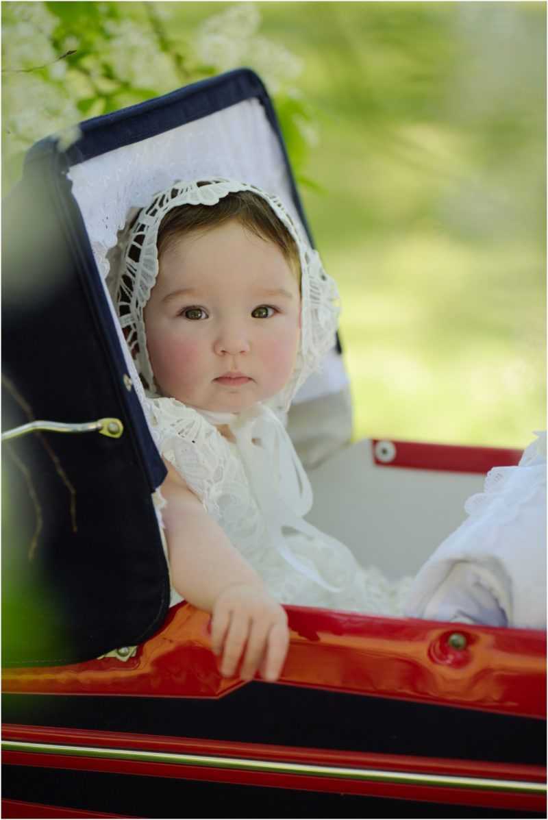 chrzest portret chrzest mała dziewczynka z wiankiem na głowie siedzi pod magnolią