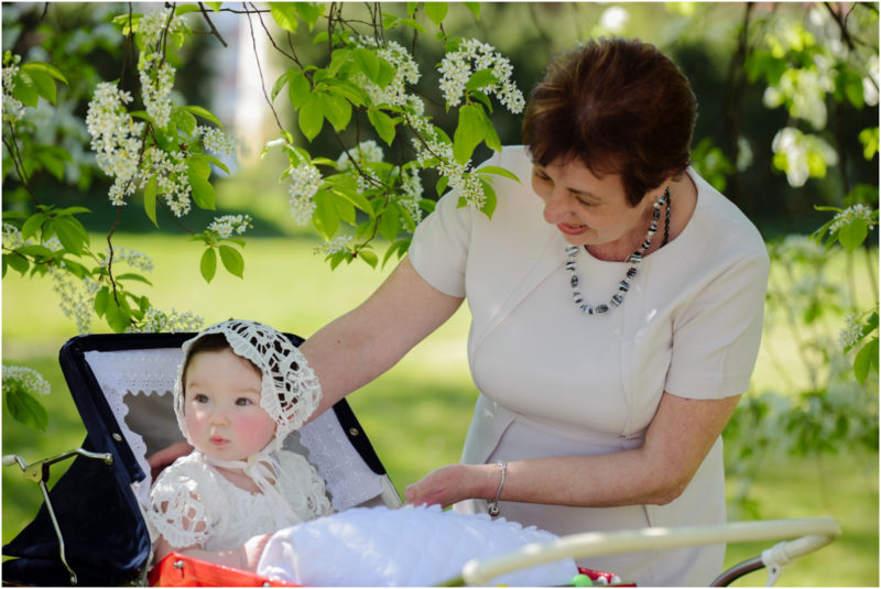 chrzest portret chrzest mała dziewczynka z wiankiem na głowie siedzi pod magnolią