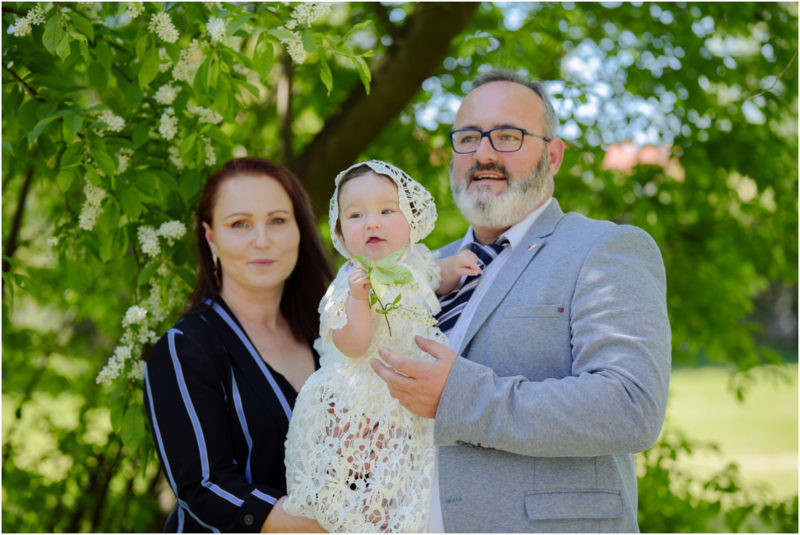 chrzest portret chrzest mała dziewczynka z wiankiem na głowie siedzi pod magnolią