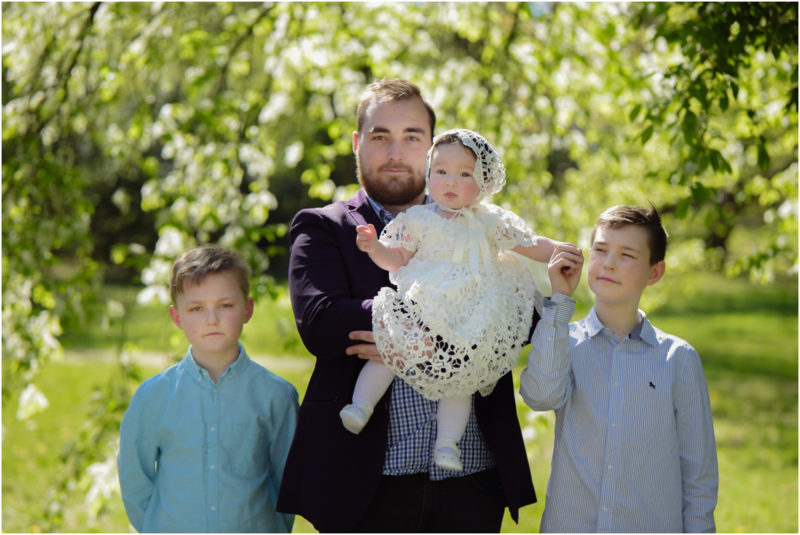 chrzest portret chrzest mała dziewczynka z wiankiem na głowie siedzi pod magnolią