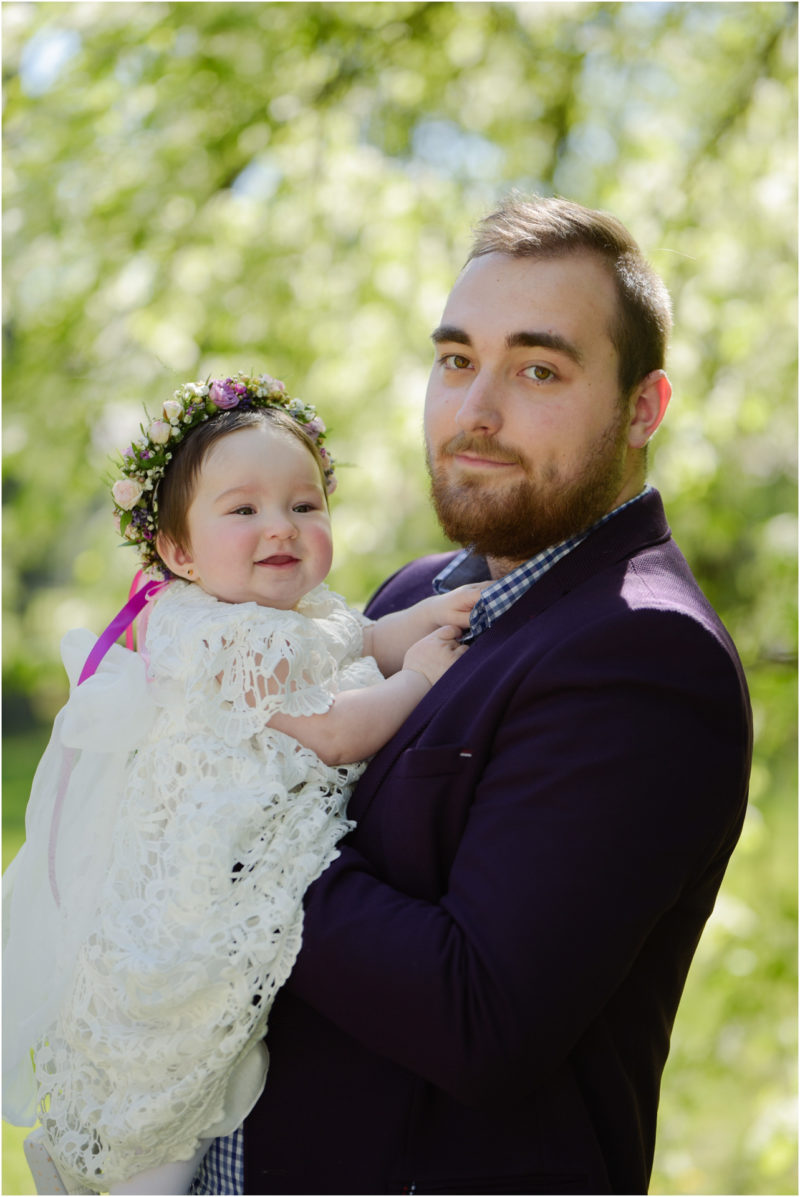 chrzest portret chrzest mała dziewczynka z wiankiem na głowie siedzi pod magnolią