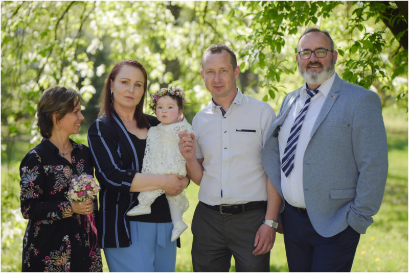 chrzest portret chrzest mała dziewczynka z wiankiem na głowie siedzi pod magnolią