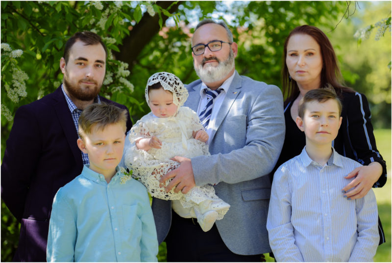 chrzest portret chrzest mała dziewczynka z wiankiem na głowie siedzi pod magnolią