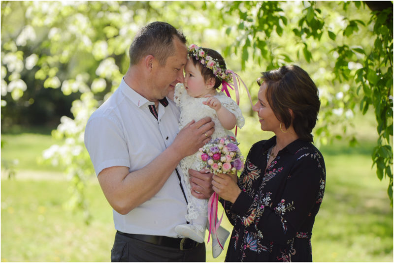 chrzest portret chrzest mała dziewczynka z wiankiem na głowie siedzi pod magnolią