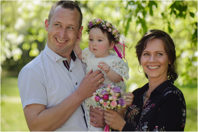 chrzest portret chrzest mała dziewczynka z wiankiem na głowie siedzi pod magnolią