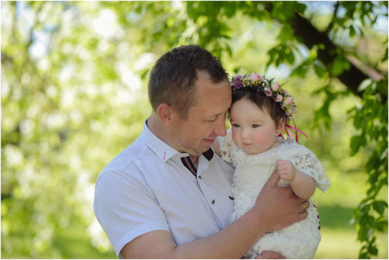 chrzest portret chrzest mała dziewczynka z wiankiem na głowie siedzi pod magnolią