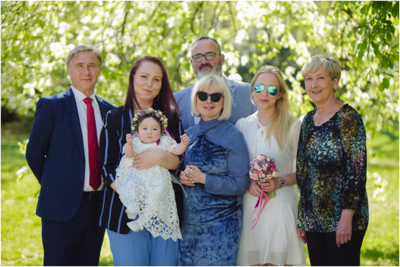 chrzest portret chrzest mała dziewczynka z wiankiem na głowie siedzi pod magnolią