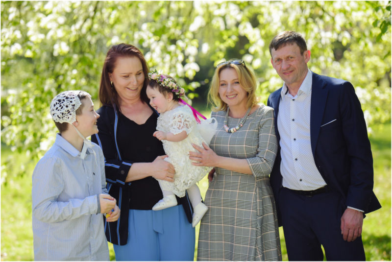 chrzest portret chrzest mała dziewczynka z wiankiem na głowie siedzi pod magnolią