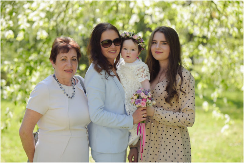 chrzest portret chrzest mała dziewczynka z wiankiem na głowie siedzi pod magnolią