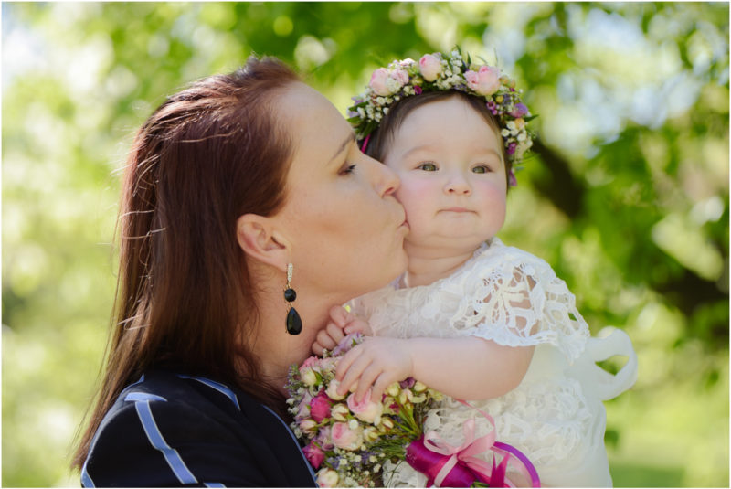 chrzest portret chrzest mała dziewczynka z wiankiem na głowie siedzi pod magnolią