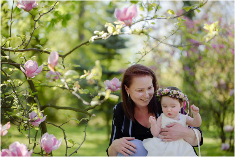 chrzest portret chrzest mała dziewczynka z wiankiem na głowie siedzi pod magnolią