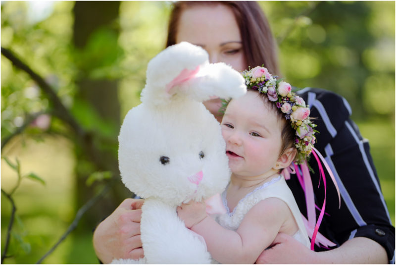 chrzest portret chrzest mała dziewczynka z wiankiem na głowie siedzi pod magnolią