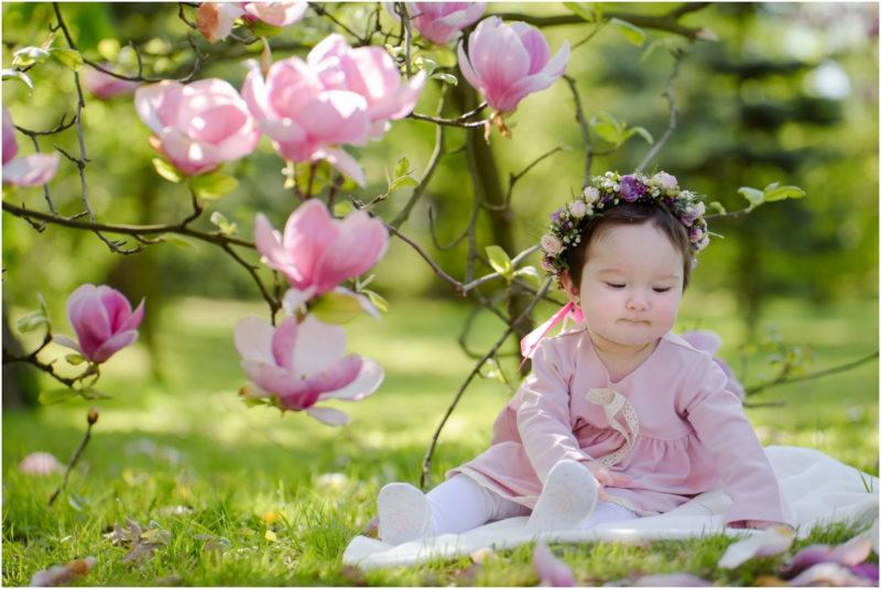 chrzest portret chrzest mała dziewczynka z wiankiem na głowie siedzi pod magnolią