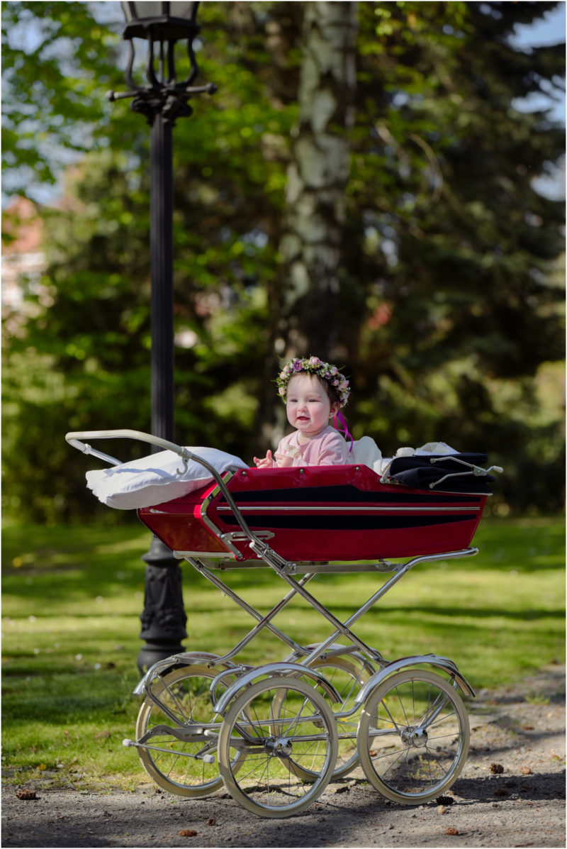 chrzest portret chrzest mała dziewczynka z wiankiem na głowie siedzi pod magnolią