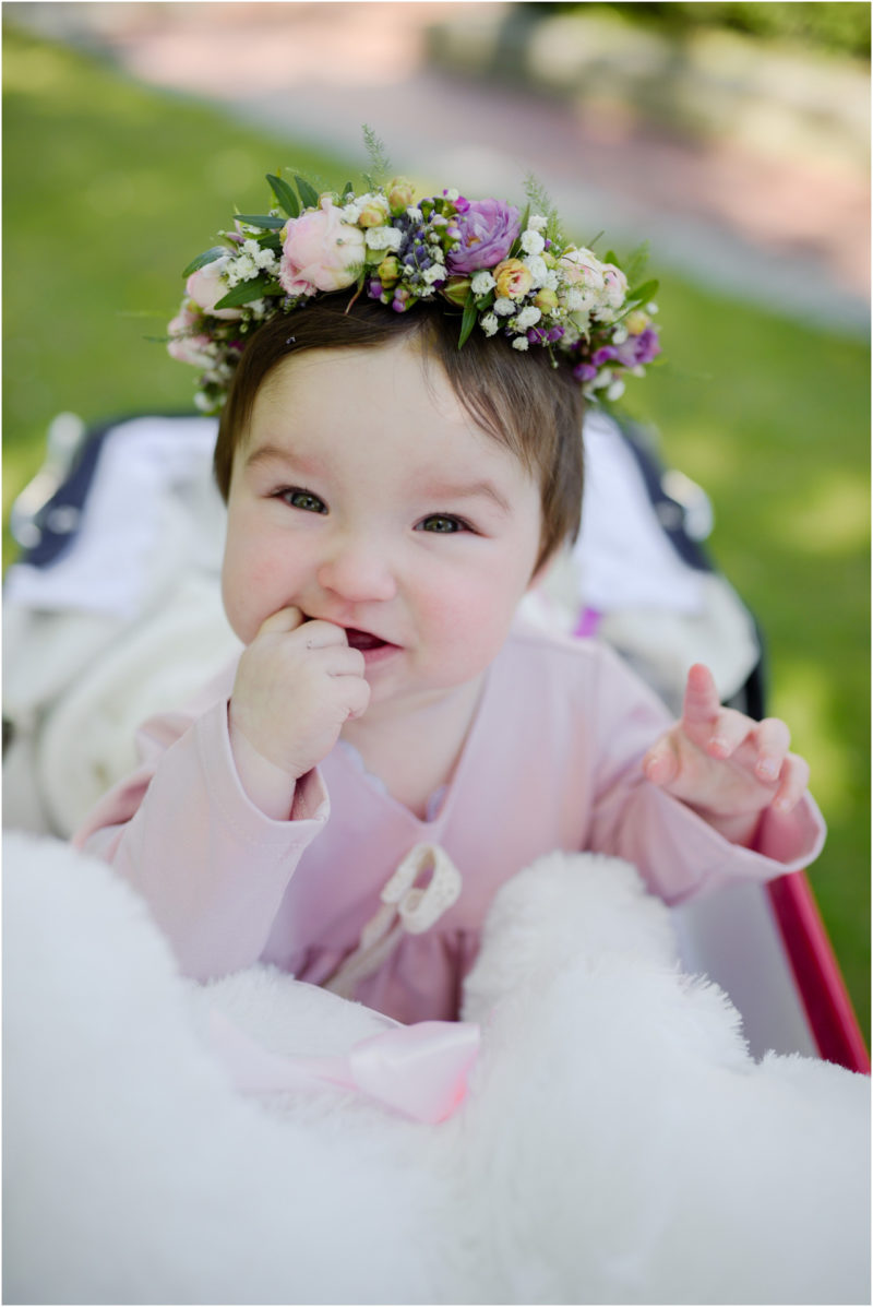 chrzest portret chrzest mała dziewczynka z wiankiem na głowie siedzi pod magnolią