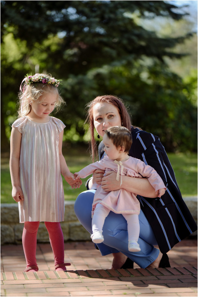 chrzest portret chrzest mała dziewczynka z wiankiem na głowie siedzi pod magnolią