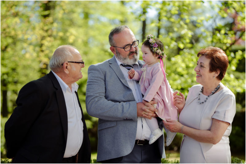 chrzest portret chrzest mała dziewczynka z wiankiem na głowie siedzi pod magnolią