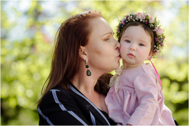 chrzest portret chrzest mała dziewczynka z wiankiem na głowie siedzi pod magnolią