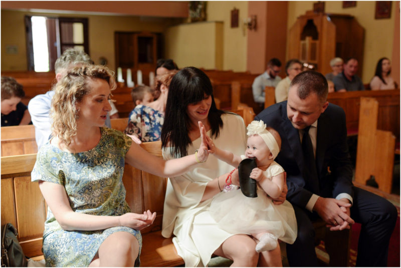 chrzest Wrocław fotografia chrzest Wrocłąw mała dziewczynka siedi na trwaie w parku