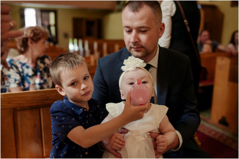 chrzest Wrocław fotografia chrzest Wrocłąw mała dziewczynka siedi na trwaie w parku