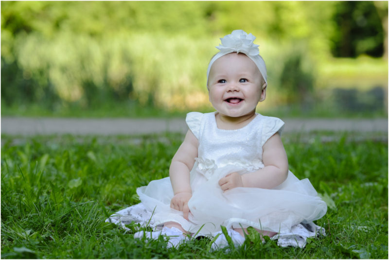 chrzest Wrocław fotografia chrzest Wrocłąw mała dziewczynka siedi na trwaie w parku
