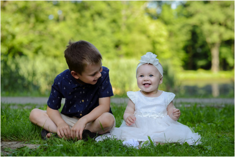 chrzest Wrocław fotografia chrzest Wrocłąw mała dziewczynka siedi na trwaie w parku