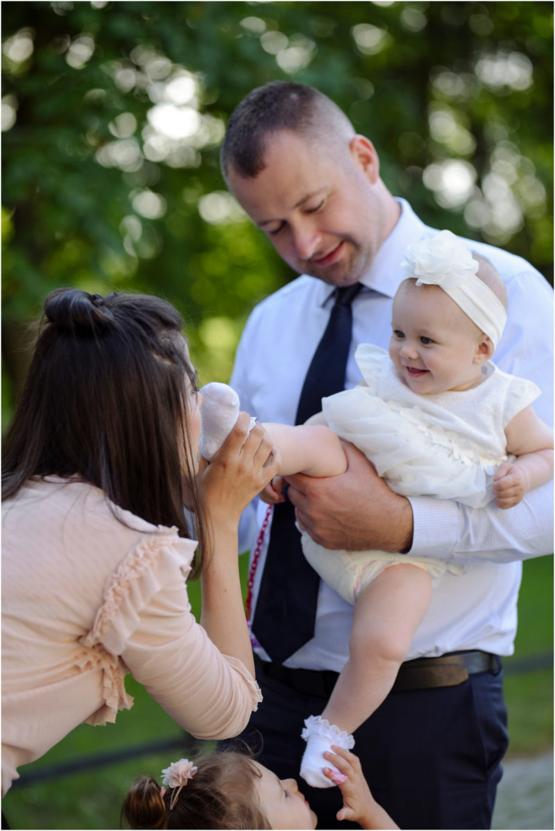 chrzest Wrocław fotografia chrzest Wrocłąw mała dziewczynka siedi na trwaie w parku