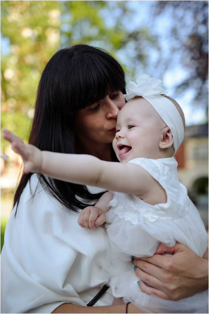 chrzest Wrocław fotografia chrzest Wrocłąw mała dziewczynka siedi na trwaie w parku